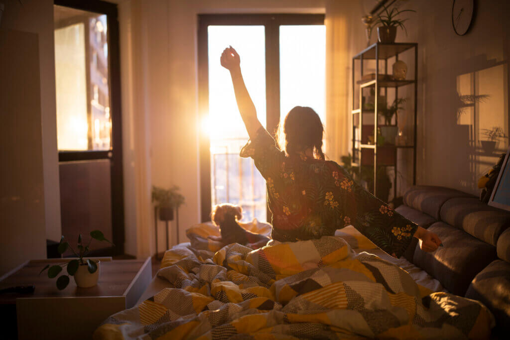 Woman wakes up to sunrise and stretches